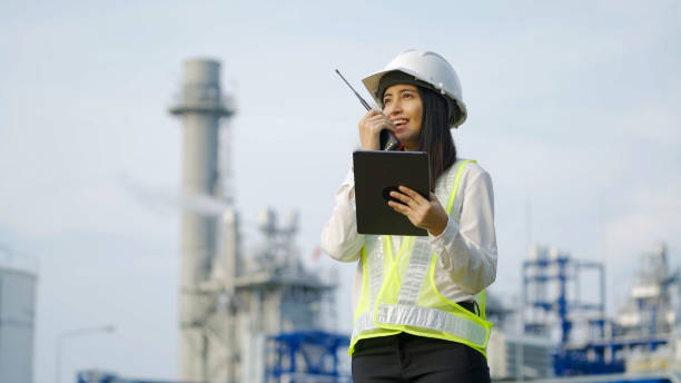 Two industrial engineer using digital tablet for work and discussing against the background of electrical power plant at night time. stock photo