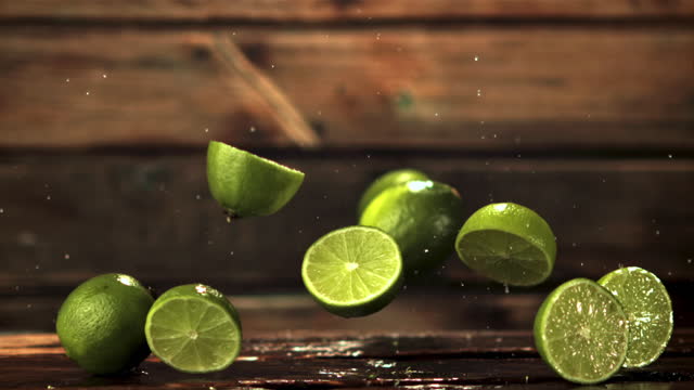 Super slow motion pieces of fresh lime fall on the table. Filmed on a high-speed camera at 1000 fps.