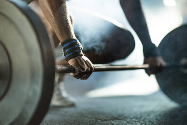 istock Unrecognizable athlete exercising with barbell in a gym. 1323465180