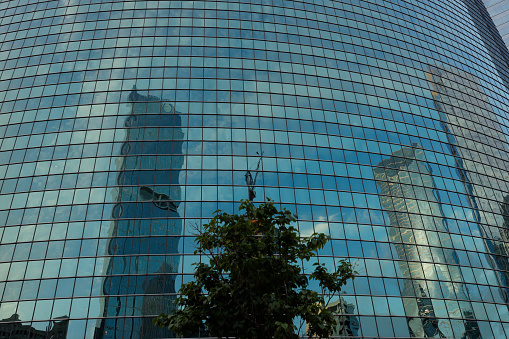 A low angle shot of a tall glass architectural building with trees in the foreground in London, United Kingdom