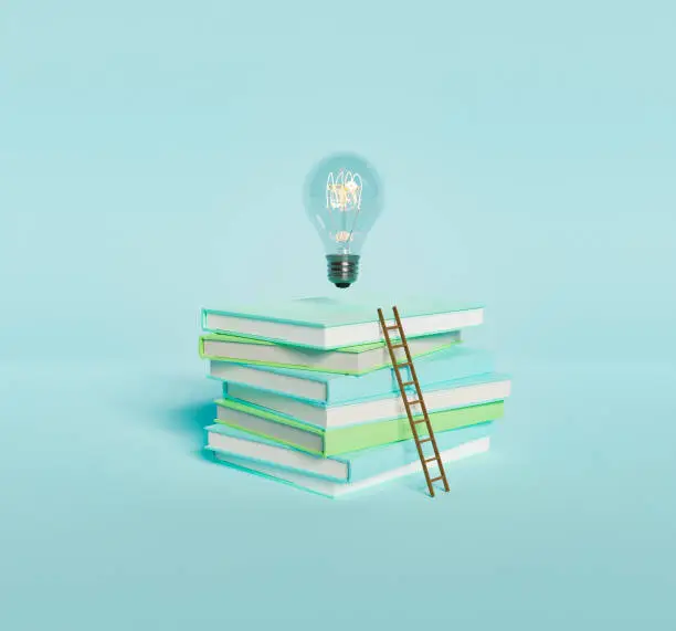 Photo of Stack of books with light bulb and ladder