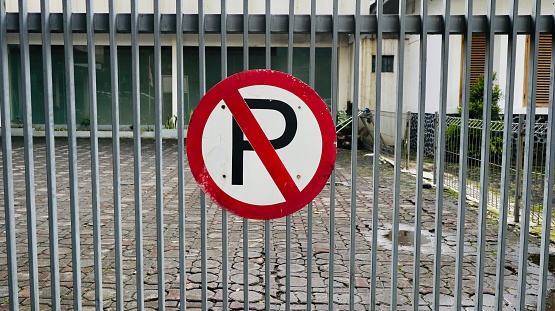 A no parking sign or symbol is placed on the fence of a house and of course you cannot park in this place
