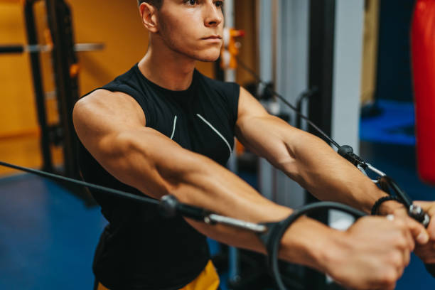 istock Handsome man doing triceps exercise with pulley in gym 1323472141