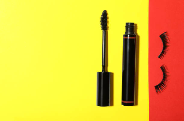 istock Black mascara and fake eyelashes on color background, flat lay with space for text. Makeup product 1323472805