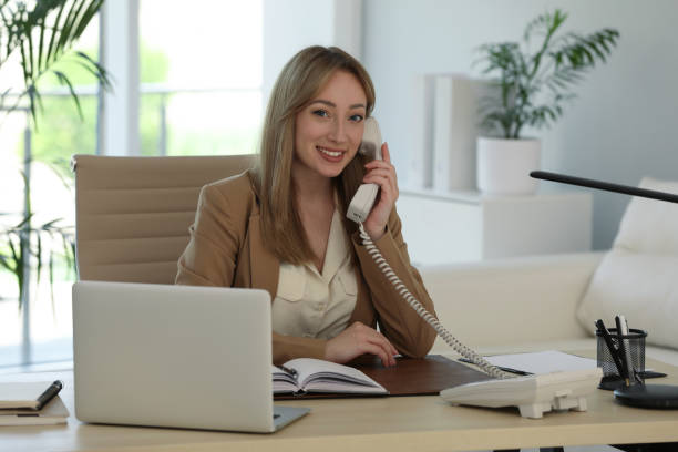 istock Secretary talking on phone at wooden table in office 1323472852