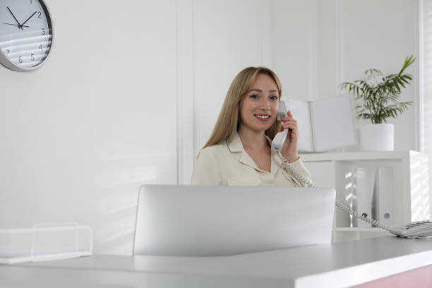 istock Receptionist talking on phone at countertop in office, space for text 1323473167