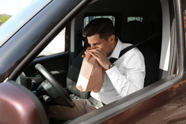 istock Man with paper bag suffering from nausea in car 1323473266