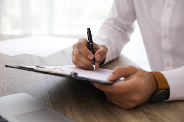 istock Businessman signing document at table indoors, closeup 1323473607