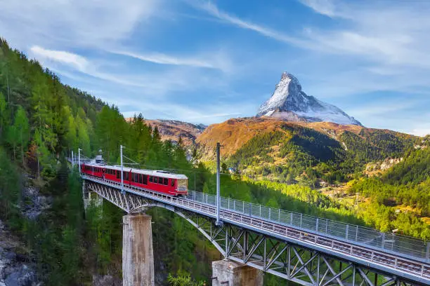 Zermatt, Switzerland. Gornergrat red tourist train on the bridge and Matterhorn peak panorama in Swiss Alps