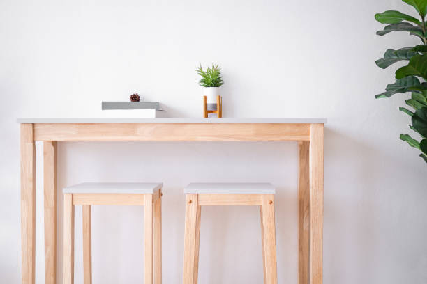 istock Realistic artificial tree in vase on wooden table with chair and wall white cement background. 1323476630