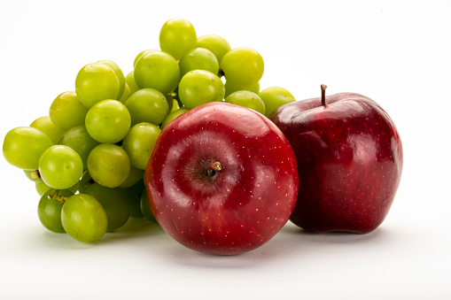 Fresh red apples and a bunch of green grapes on white background.