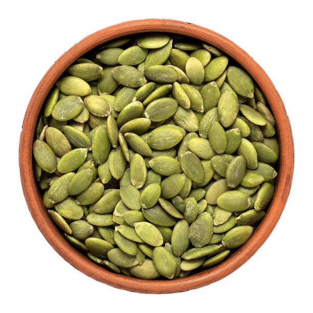 istock Pumpkin seeds in a bowl isolated on white background. Top view. 1323478314