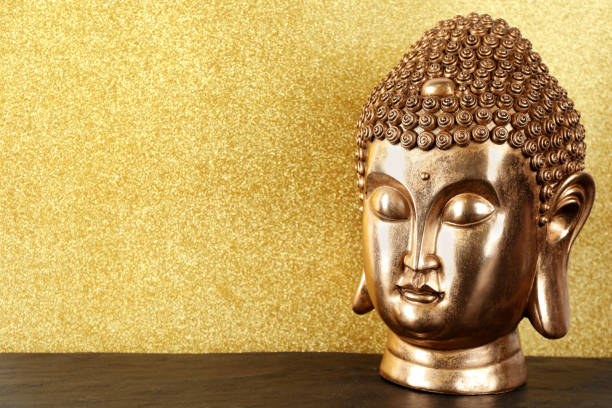 istock Buddha statue on table against golden background. Space for text 1323480899