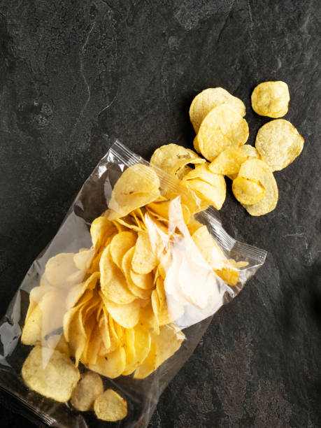 istock Chips spilling out of an open bag, Potato chips package, Potato chips, Chips on Black Background, Chips 1323482850