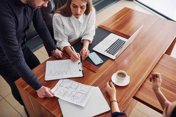 istock Top view of three people that working in the office by laptop and with documents 1323482977