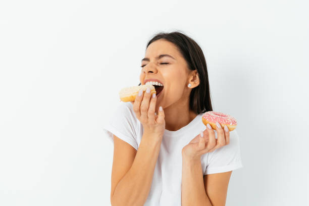 istock Beautiful young woman eating donuts 1323483692