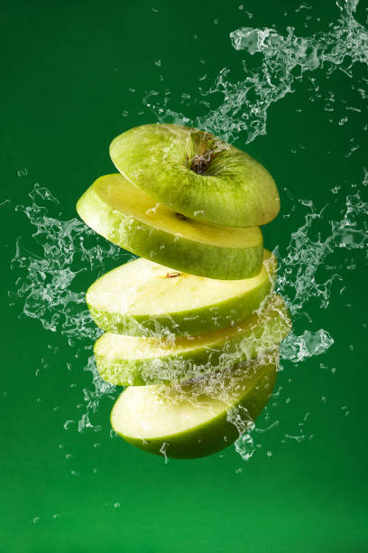 istock Sliced green apple cut splashing water 1323485360
