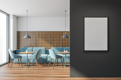 Dining room interior in public place, round wooden tables and blue sofa on parquet floor, minimalist design of restaurant. Windows and mockup blank poster on black wall, 3D rendering no people
