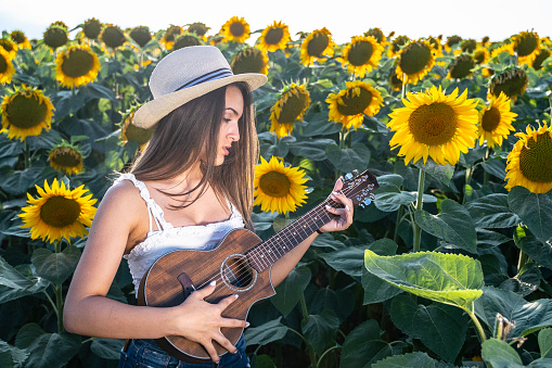 Girl in the blooming sunflowers on a brightly lit day. Having fun in nature.
