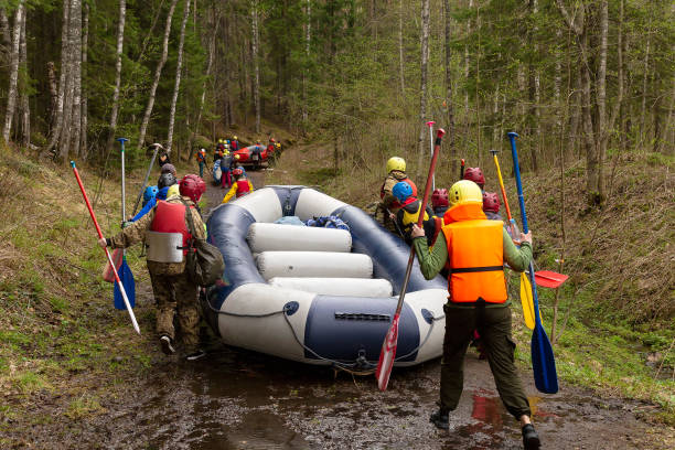 un groupe de touristes transporte le bateau en caoutchouc le long de la rive jusqu’au lieu de descente le long de la rivière - fitness trainer photos et images de collection