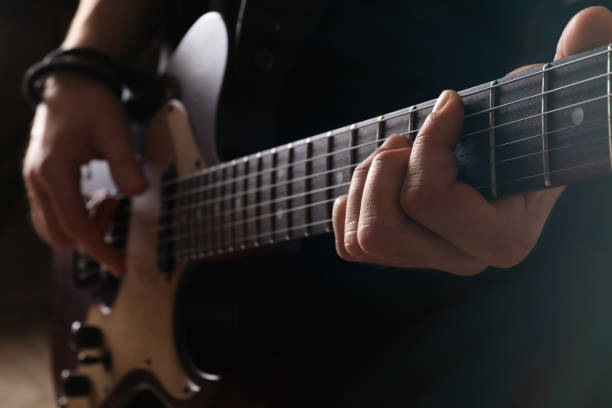 istock Man playing electric guitar on blurred background, closeup. Rock music 1323488078