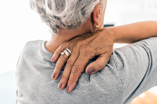 Photo of senior woman holding her neck in pain