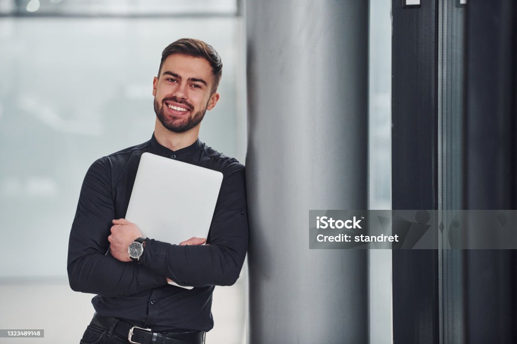 Junge bärtige Kerl in eleganten Kleidern stehen drinnen vor grauem Hintergrund - Lizenzfrei Unternehmer Stock-Foto