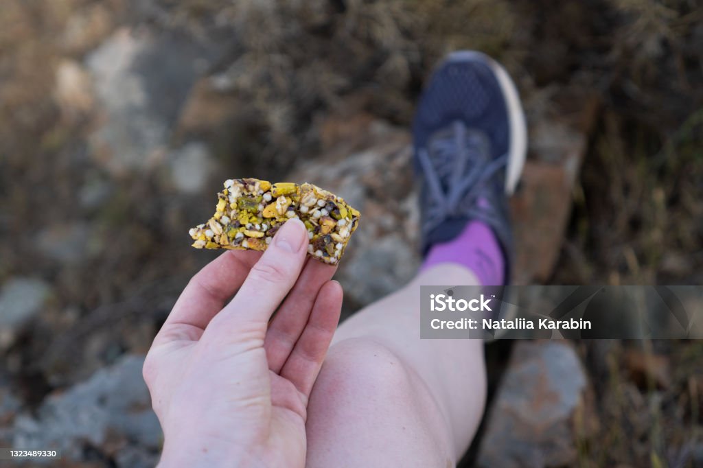 Sweet healthy and hearty food. Hand holding fitness bar. Healthy sweets for runners. Bar of nuts and honey for hiking Sweet healthy and hearty food. Hand holding fitness bar. Healthy sweets for runners. Bar of nuts and honey for hiking. High quality photo Hiking Stock Photo