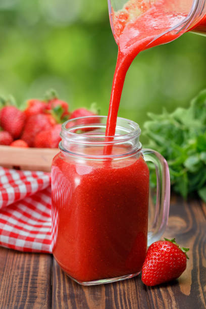 istock strawberry juice pouring from jug into glass 1323489419