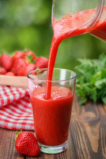 istock strawberry smoothie pouring from jug into glass 1323492225