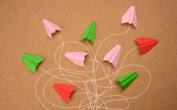 istock group of multicolored paper planes with long tangled paths on a brown background. 1323494709
