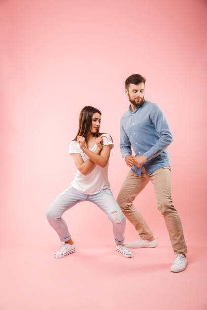Full length portrait of a happy young couple Full length portrait of a happy young couple dancing together isolated over pink background isolated color stock pictures, royalty-free photos & images