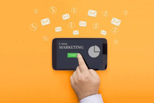 Conceptual photo of email marketing. Finger presses on the screen of a mobile device with the inscription Email Marketing.