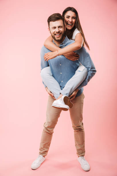 Full length portrait of a smiling young man Full length portrait of a smiling young man giving his girlfriend piggyback ride isolated over pink background boyfriend stock pictures, royalty-free photos & images