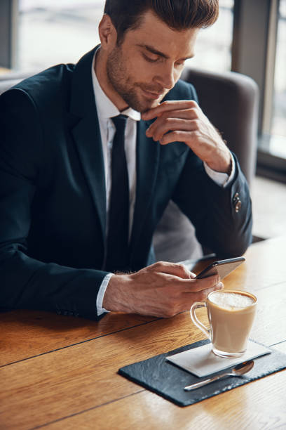 istock Handsome young businessman in full suit using smart phone 1323497279