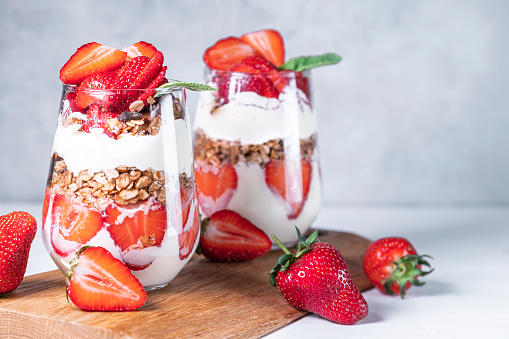 Healthy breakfast of strawberry parfaits made with fresh strawberry, yogurt and muesli in glasses.