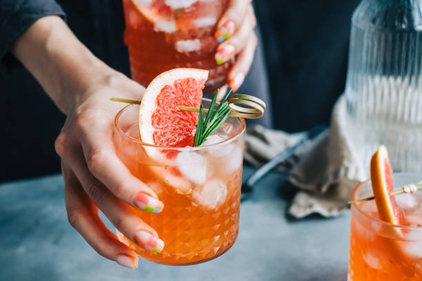 la camarera femenina sostiene vasos de limonada de cóctel de pomelo con hielo y romero. - home interior cocktail bar women fotografías e imágenes de stock