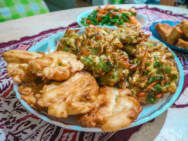Vegetable and banana fritters (gorengan pisang dan bakwan) Indonesian homey food, Vegetable and banana fritters (gorengan pisang dan bakwan) served in a plate with batik clothes in the background gorengan stock pictures, royalty-free photos & images