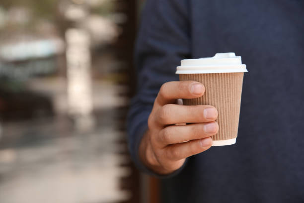 istock Man with takeaway coffee cup outdoors, closeup 1323500897