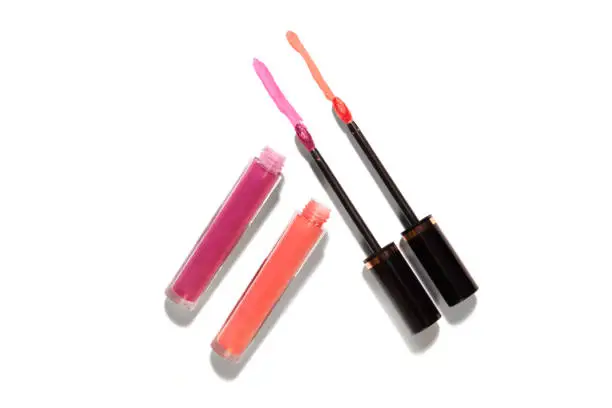 Lip glass liquid stick isolated on white with strong harsh shadows product for magazine layout pink and orange color