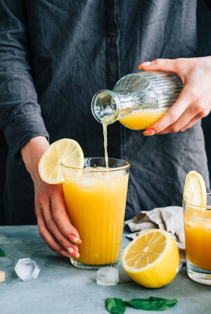 istock Female bartender pours fresh lemonade from bootle in glass with ice. 1323502450