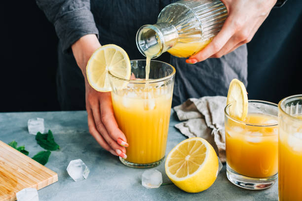 istock Female bartender pours fresh lemonade from bootle in glass with ice. 1323502785