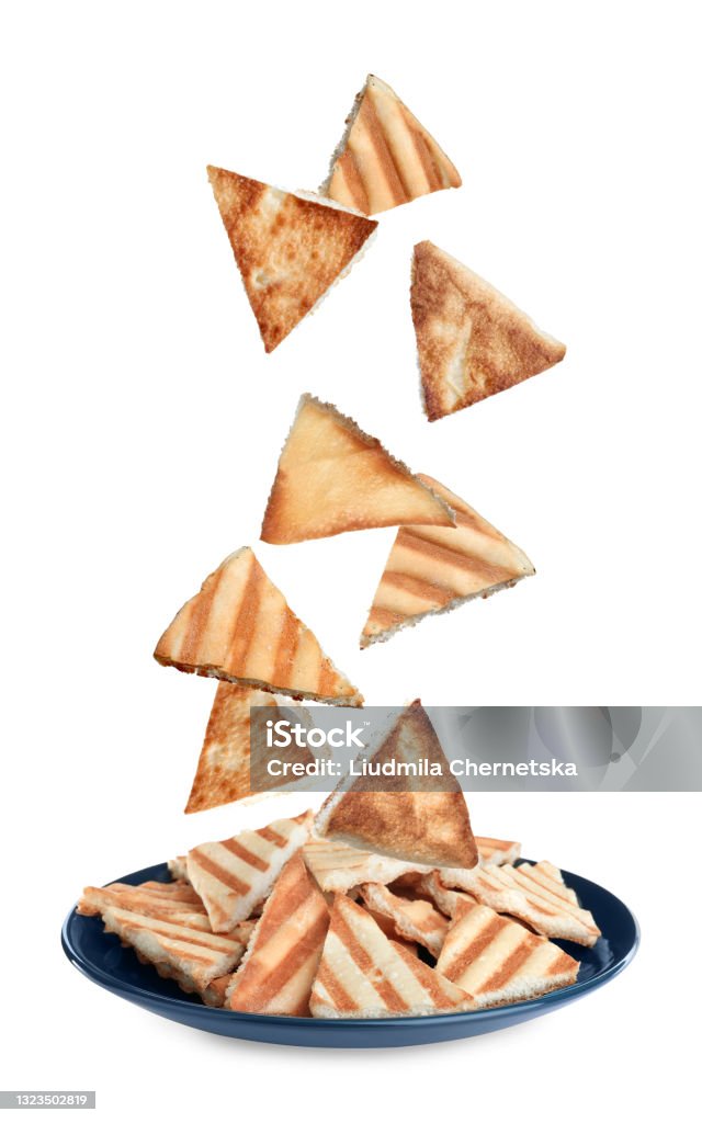 Delicious crispy pita chips falling into plate on white background Pita Bread Stock Photo