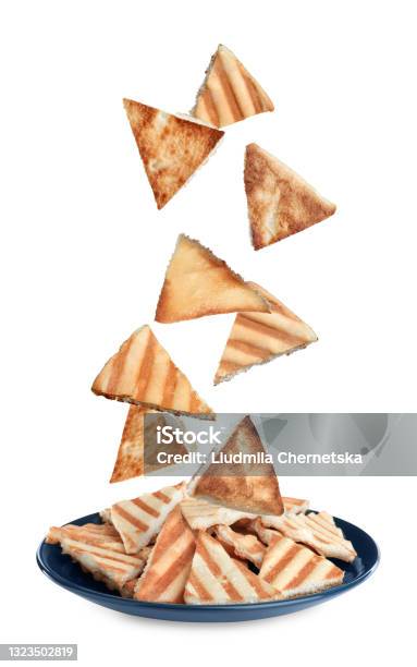Delicious Crispy Pita Chips Falling Into Plate On White Background Stock Photo - Download Image Now