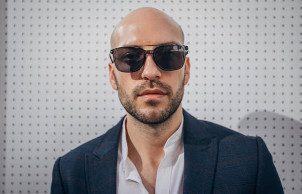 Mature businessman with a serious expression wearing sunglasses, conveying a sense of authority, mystery, or hidden intentions