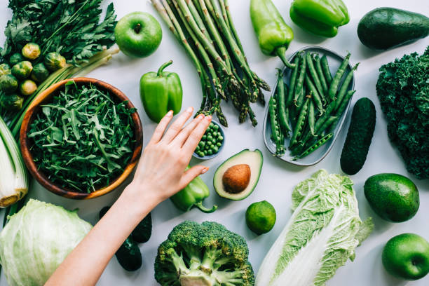 mani da donna che prendono piselli verdi dalla tavola con verdure fresche, concetto di alimentazione sana. - leaf vegetable asparagus green vegetable foto e immagini stock
