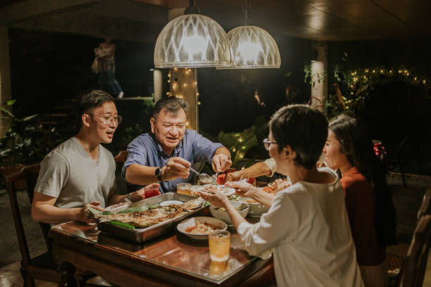 papá tailandés dando algo de comida a la esposa al lado de la foto de archivo de la familia - cultura oriental fotografías e imágenes de stock