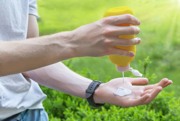 istock Caucasian man's hands with sunscreen (sun cream) plastic container on natural green background. 1323506939