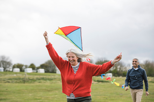 Senior friends flying a kite together in a field in the North East of England.