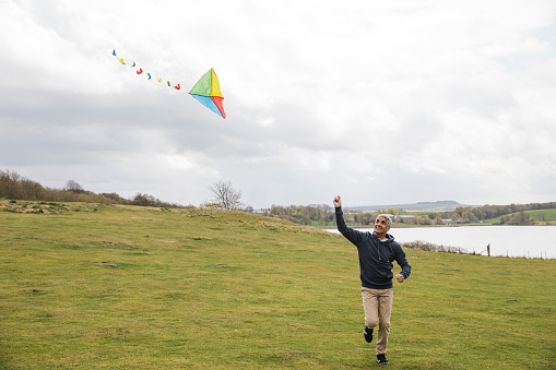 Man flying a kite in a field while running in the North East of England.